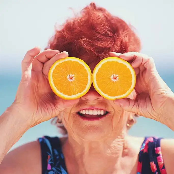 Woman at the beach holding oranges over her eyes