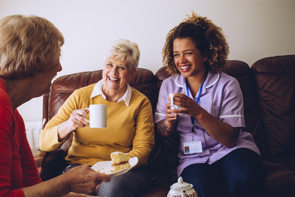 Senior caregiver having tea with residents