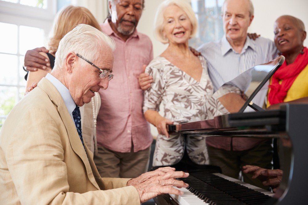 Seniors singing and playing piano together in retirement community