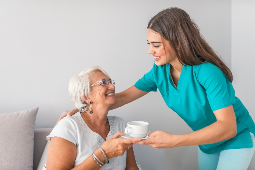 Caregiver giving tea to senior woman