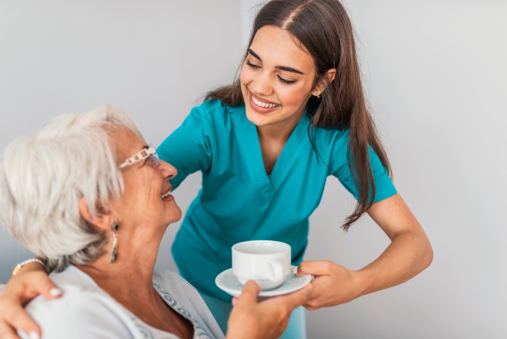Caregiver handing coffee or tea to memory care resident