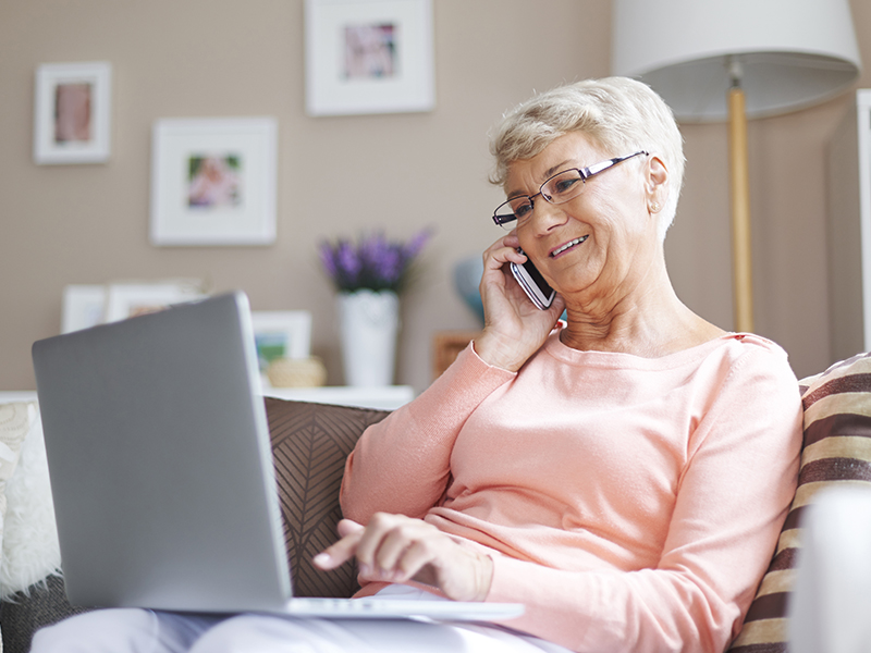 Senior woman using phone and laptop